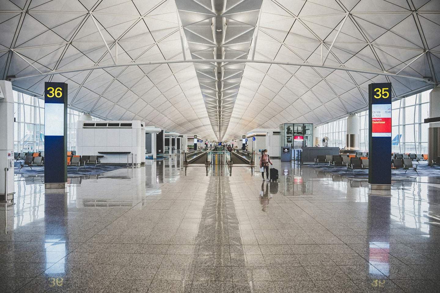 A bright airport concourse with a steel roof and a polished floor