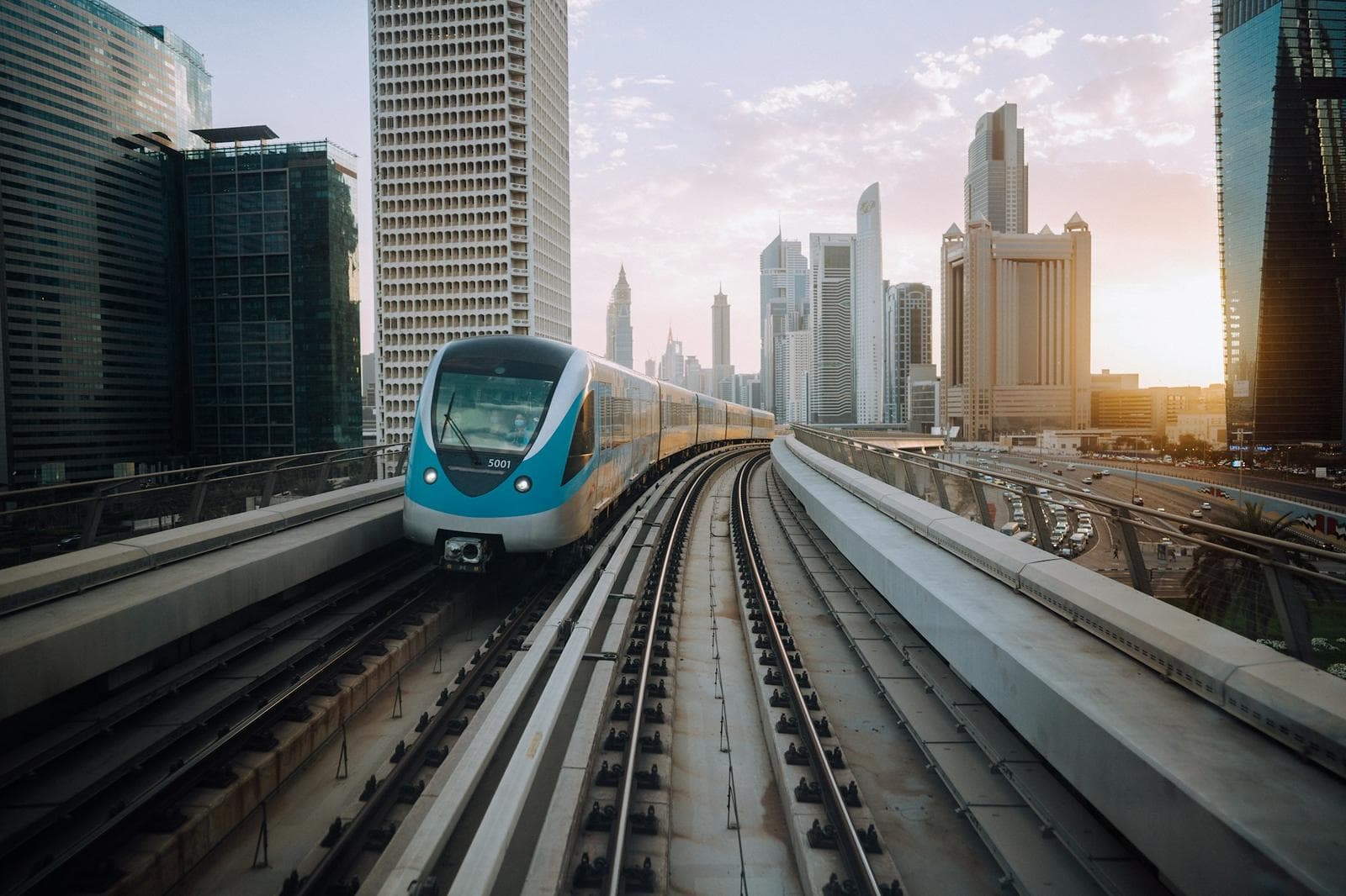 A Dubai Metro train heading toward the downtown skyline at golden hour