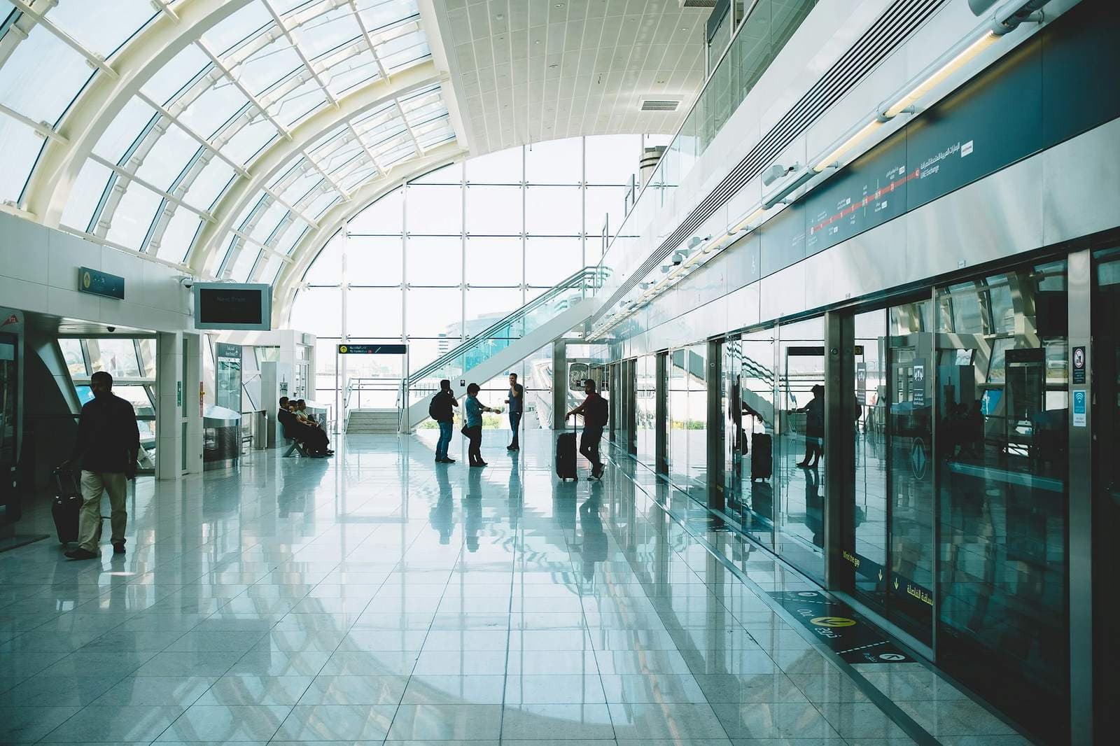 Travellers with luggage walking through a bright metro station concourse in Dubai