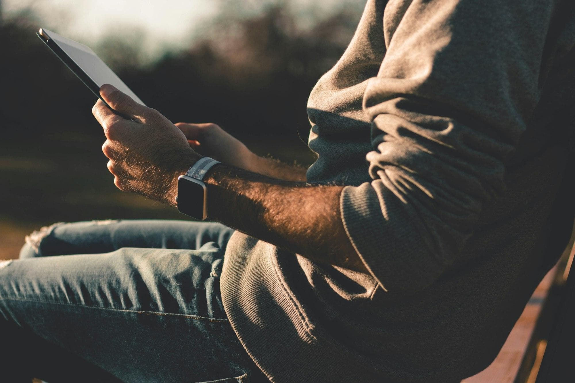 A person holding a tablet in warm evening light