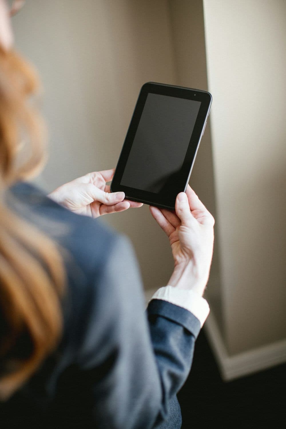 A person in a blazer holding a tablet in a quiet office