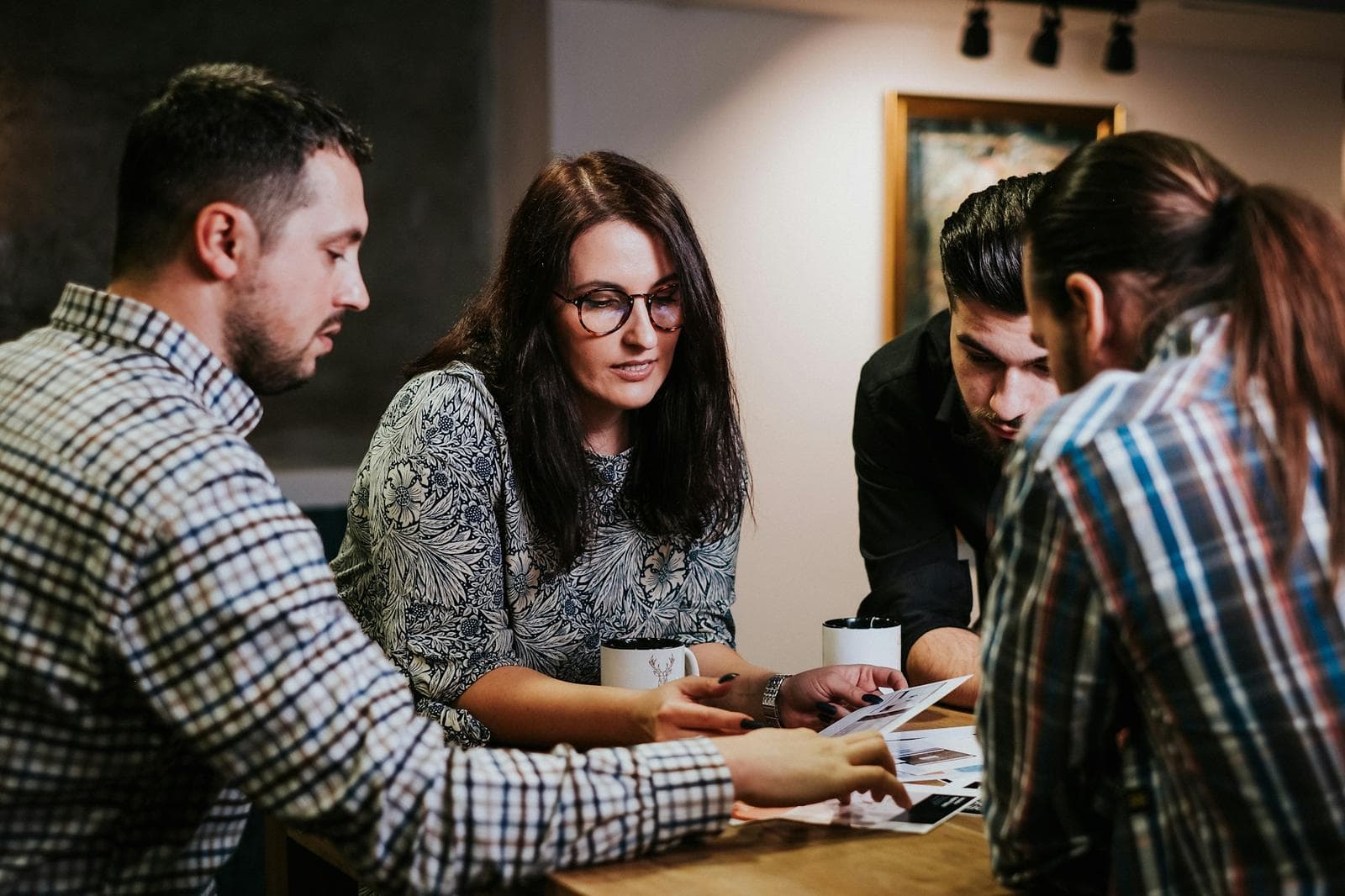 Colleagues reviewing printed pages around a wooden table