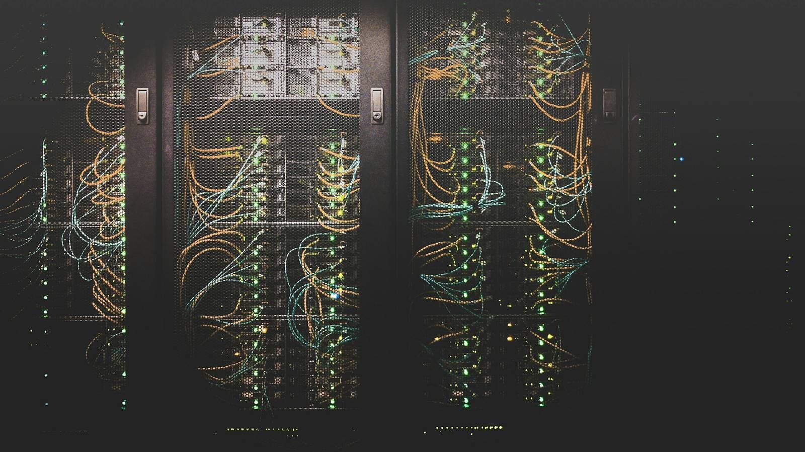 Server racks with amber and teal network cables and status lights