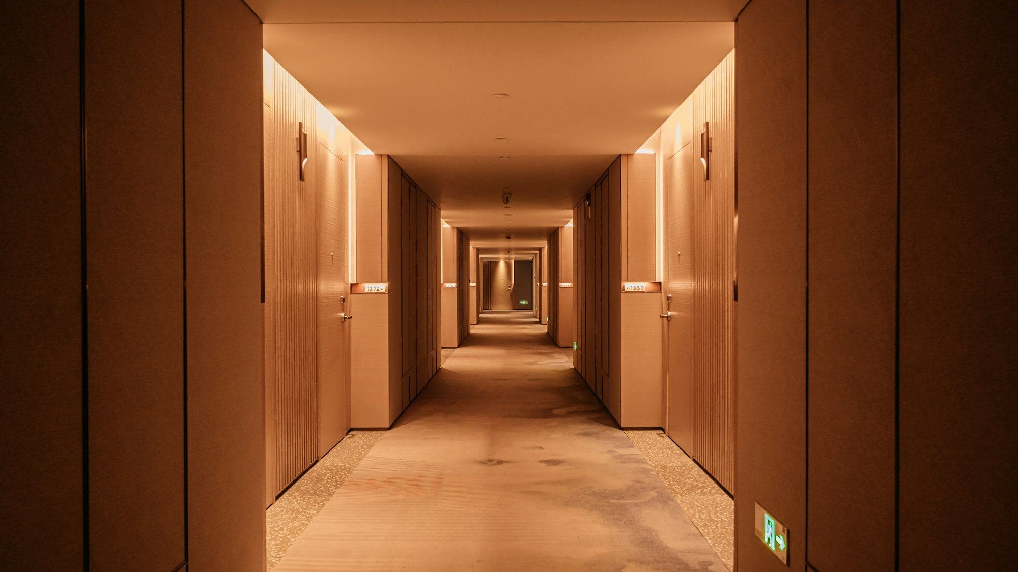 A warmly lit hotel corridor with timber doors